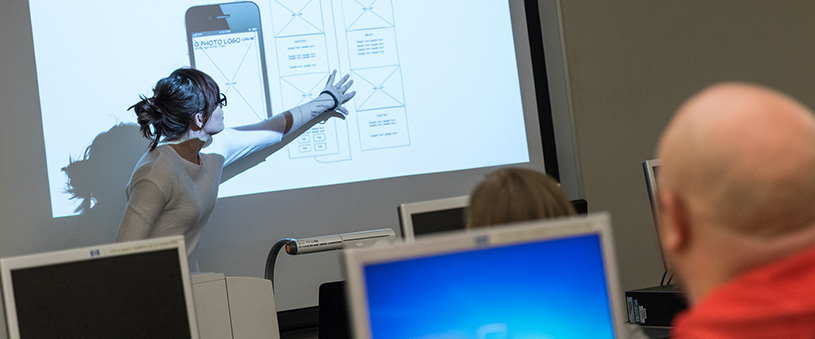 A faculty member at the front of a classroom.